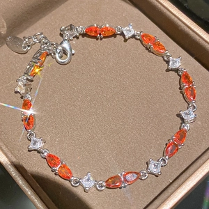 Detailansicht eines funkelnden Armbands mit orangefarbenen und klaren Zirkonia-Steinen