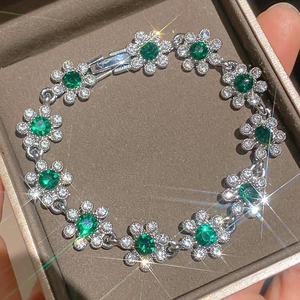 Elegantes Blumenarmband mit funkelnden smaragdgrünen Zirkonia-Steinen in Silberfassung.
