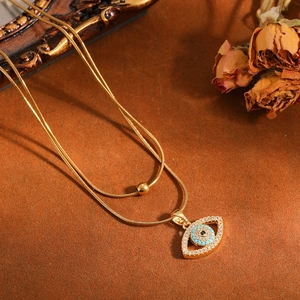 Detailopname gouden dubbellaagse ketting met turkooizen kristallen boze oog hanger