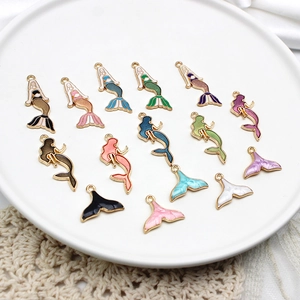 Amuletos de esmalte de sirena y cola de pez de colores en un plato de cerámica blanca