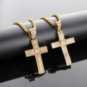 Close-up of golden iced-out cross pendants with white crystals on a box chain link