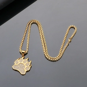 Macro view of iced out golden bear paw pendant with sparkling pavé crystals and box chain