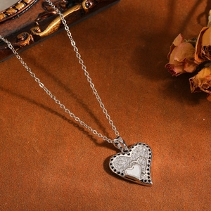 Primo piano della collana con ciondolo a cuore, pietre bianche e intarsio in conchiglia