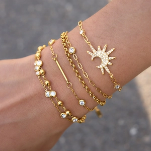 Detail view of layered gold-plated stainless steel bracelets with sparkling zircon moon charm