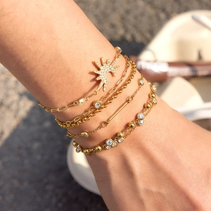 Detail showing a layered stack of 316 stainless steel gold bracelets with zircons