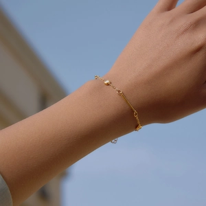 Detailed shot of a delicate gold stainless steel bracelet with zircon and bar elements