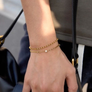 Detailed view of layered gold-tone stainless steel bracelets with zircon worn on wrist