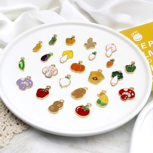 Detailed view of colorful vegetable and fruit enamel charms on a white plate.