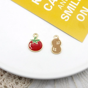 Close-up detail of tomato and peanut enamel charms with vibrant colors and gold-plated edges