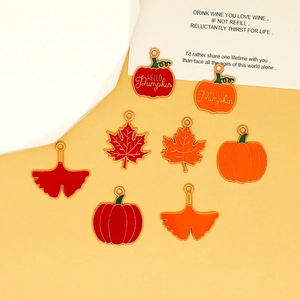 Detailed view of autumn-themed enamel charms featuring maple leaves and pumpkins for DIY