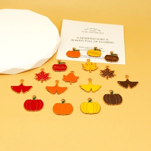 Detailed view of autumn enamel charms including maple leaves and pumpkins for DIY jewelry.