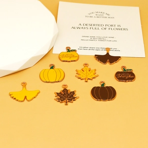 Detail view of colorful enamel Thanksgiving pumpkin and maple leaf charms for DIY jewelry