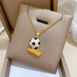 Dettaglio della collana con ciondolo calcio e scarpa in acciaio titanio su fondo oro