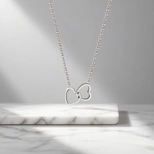 Minimalist silver interlocking double heart titanium steel necklace on marble base