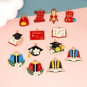 Close-up detail of various graduation theme enamel charms including bachelor hats and diplomas.