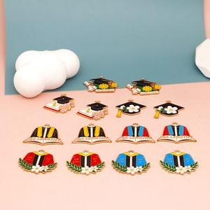 Macro detail of colorful graduation themed enamel charms with bachelor cap and book motifs