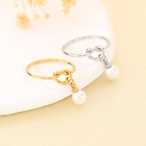 Vista dettagliata di eleganti anelli a nodo oro e argento con perle bianche pendenti