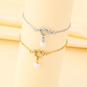 Vista dettagliata di eleganti bracciali a nodo oro e argento con ciondoli di perle bianche