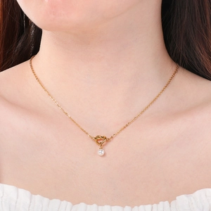 Elegante collana con nodo dorato e ciondolo di perla bianca indossata da una modella