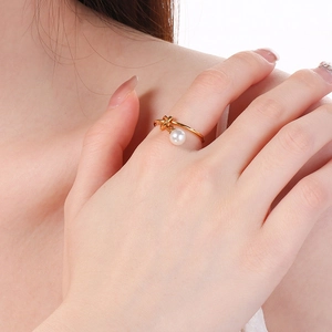 Primo piano di un elegante anello a nodo dorato con perla bianca indossato su una mano