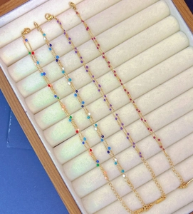 Close-up of golden stainless steel chains with colorful enamel beads and lobster clasp