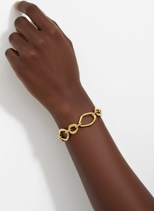 Close-up of a chunky 18k gold-plated stainless steel link bracelet on a wrist.