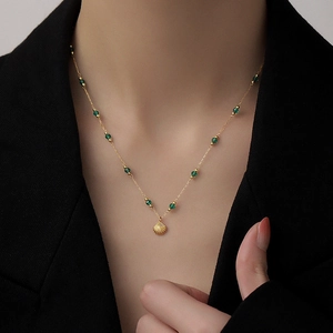 Elegant gold titanium steel necklace with green beads and shell pendant on a model