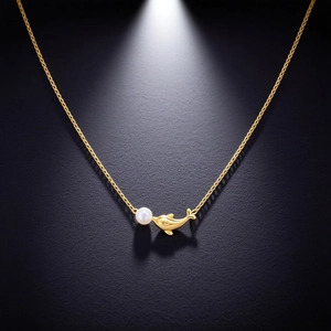 Elegant gold dolphin pendant necklace with round white pearl on a dark textured background