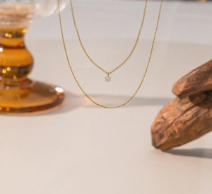 Detailed view of a double-layered gold necklace with a sparkling round zircon pendant