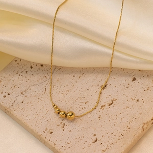 Minimalistische goldene Schlangenkette mit polierten Metallperlen auf Seide und Naturstein