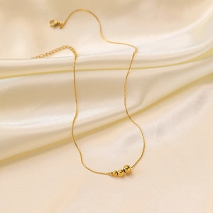 Minimalistische Goldperlenkette mit fünf abgestuften Kugeln auf Seidenhintergrund