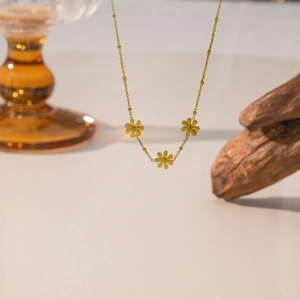 Elegante collana in titanio dorato con tre ciondoli a margherita e catena a sfere