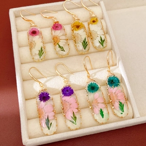 Detailed macro view of elegant handmade resin oval earrings with embedded dried flowers