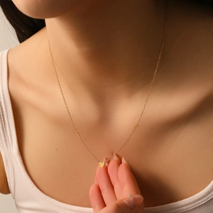Minimalist gold heart necklace set with three small heart pendants on a fine chain
