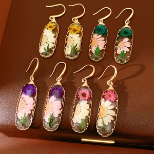 A diverse collection of handmade oval resin earrings featuring real dried flowers in gold hooks