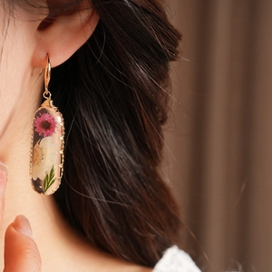 Close-up of elegant resin oval earrings with preserved dried flowers