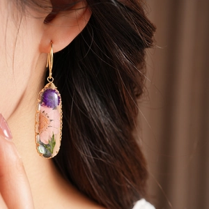 Close-up detail of sweet oval resin earrings featuring real dried pink flowers