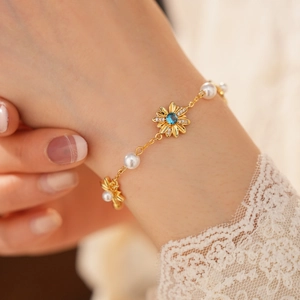 Dettaglio ravvicinato di un braccialetto a fiori placcato oro con zircone blu e perle
