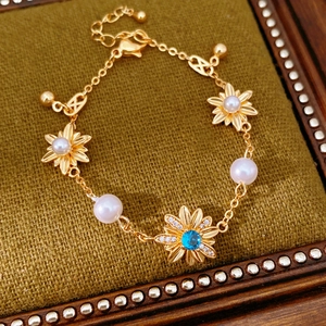 Dettaglio ravvicinato di un braccialetto vintage placcato oro con fiori e perle bianche