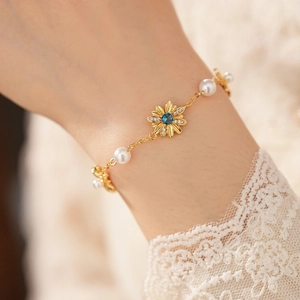 Primo piano di un elegante bracciale vintage placcato oro con margherita e perle al polso