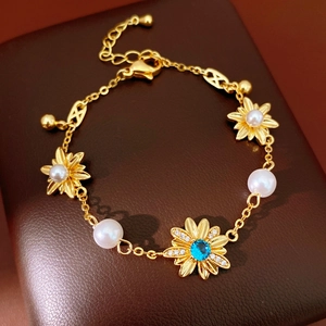 Dettaglio di un bracciale a fiori placcato oro con zircone blu e perle bianche
