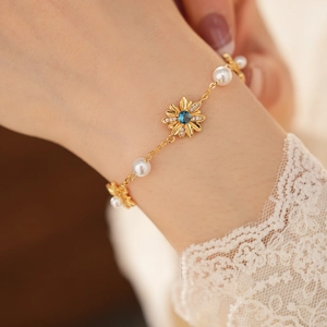 Dettaglio di bracciale vintage placcato oro con margherita in zircone e perle bianche
