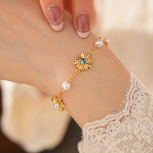 Dettaglio ravvicinato di un bracciale vintage placcato oro con fiori di zirconi e perle