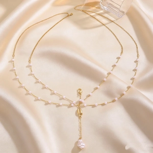 Close-up detail of sexy gold multi-layer body chain featuring shell and pearl charms