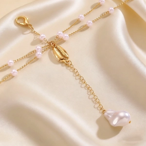 Close-up of gold shell charm and pink pearl beads on multi-layered women's chest chain