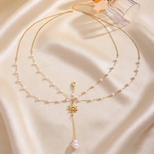Detailed view of a multi-layer gold body chain featuring pearls and a sun pendant charm.