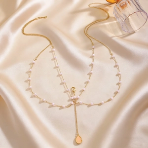 Detailed view of elegant multi-layer gold body chain with pink pearls and teardrop pendant.