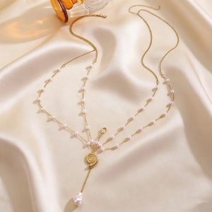 Detailed view of elegant gold-tone multi-layer chest chain with shell and pearl accents.