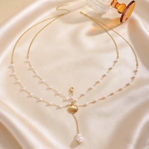 Detailed view of layered gold body chain with shell pendant and baroque pearl