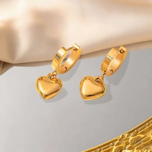 Boucles d'oreilles cœur dorées polies sur fond satiné avec surface réfléchissante